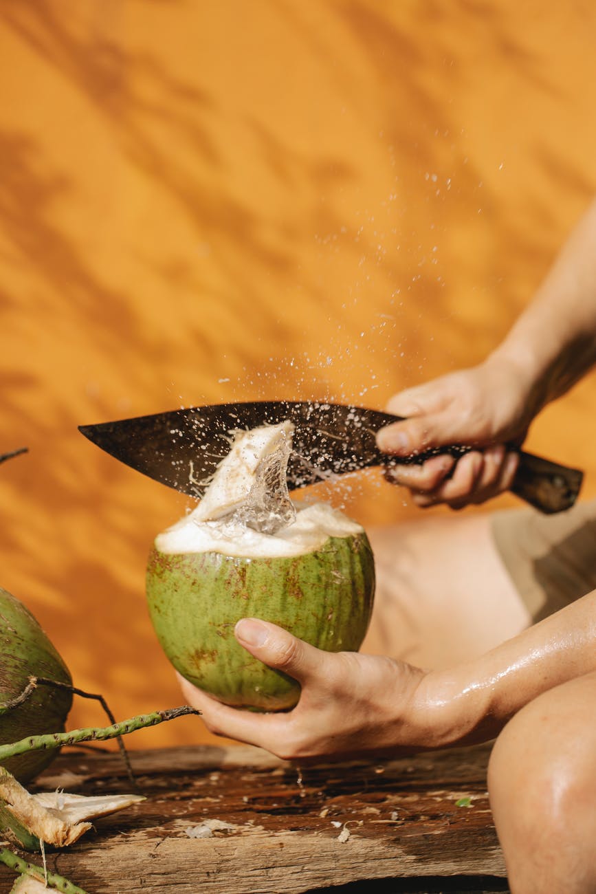 crop person with knife and green coconut